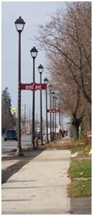 street view looking down the road with multiple street lights with road signs on the street light posts